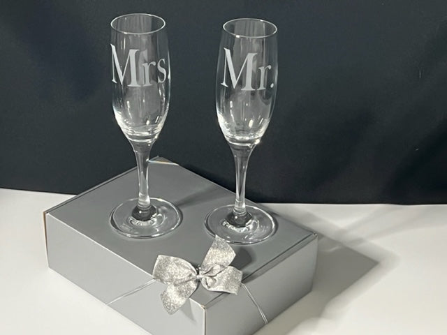 two champagne flutes on a gift box that have Mrs. and Mr. etched on 